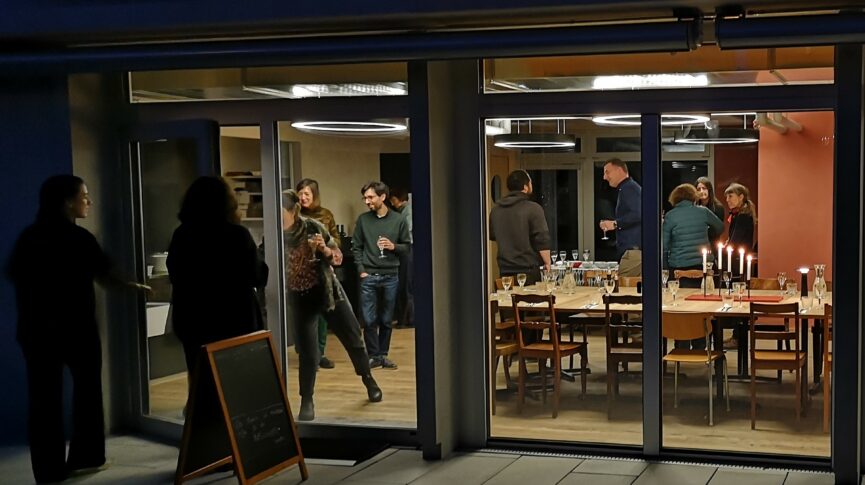 Blick ins Bistro vom Platz nachts mit Gästen Siedlung Winkelhalden