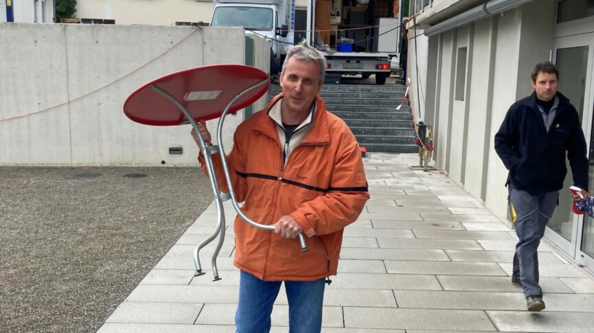 Lächelnder Bewohner trägt Tisch in die Siedlung.